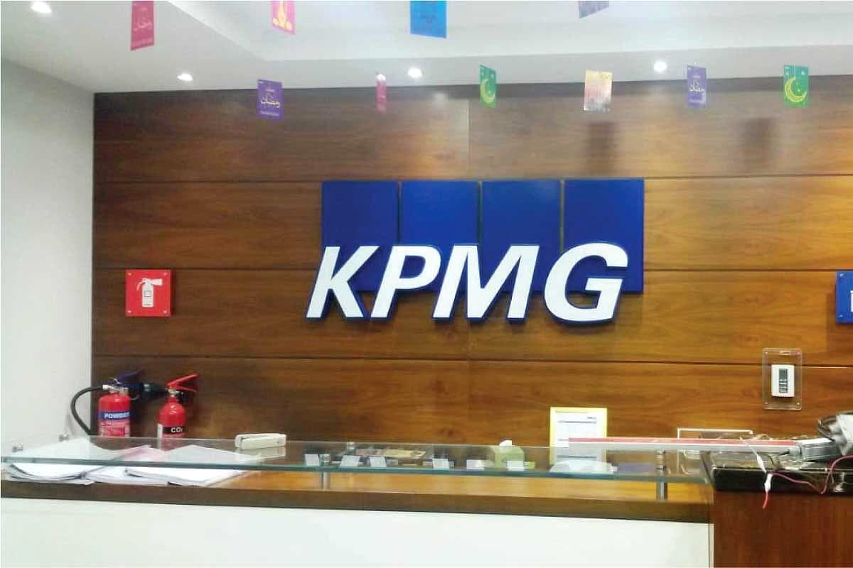 Blue KPMG letters on a wood-panelled wall above a reception counter