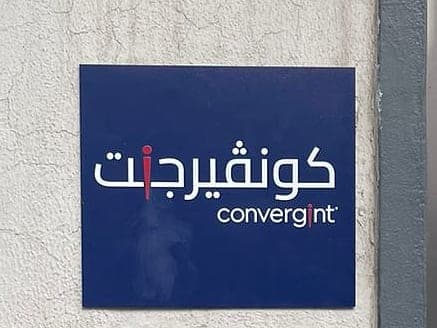 Blue bilingual Convergint name plate with white and red lettering on a rendered wall