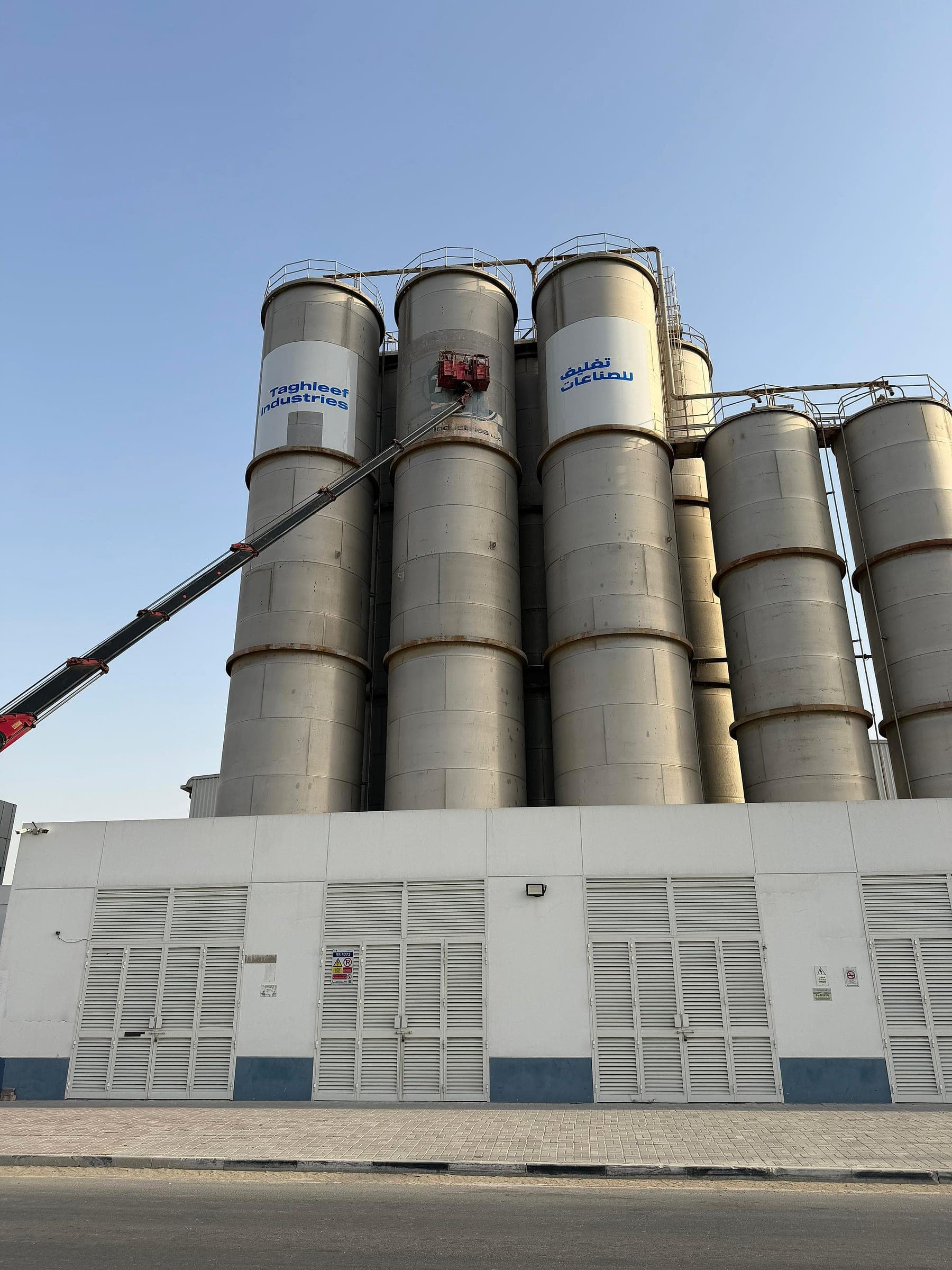 Crane basket lifting installers up the Taghleef Industries silos to fit the branding