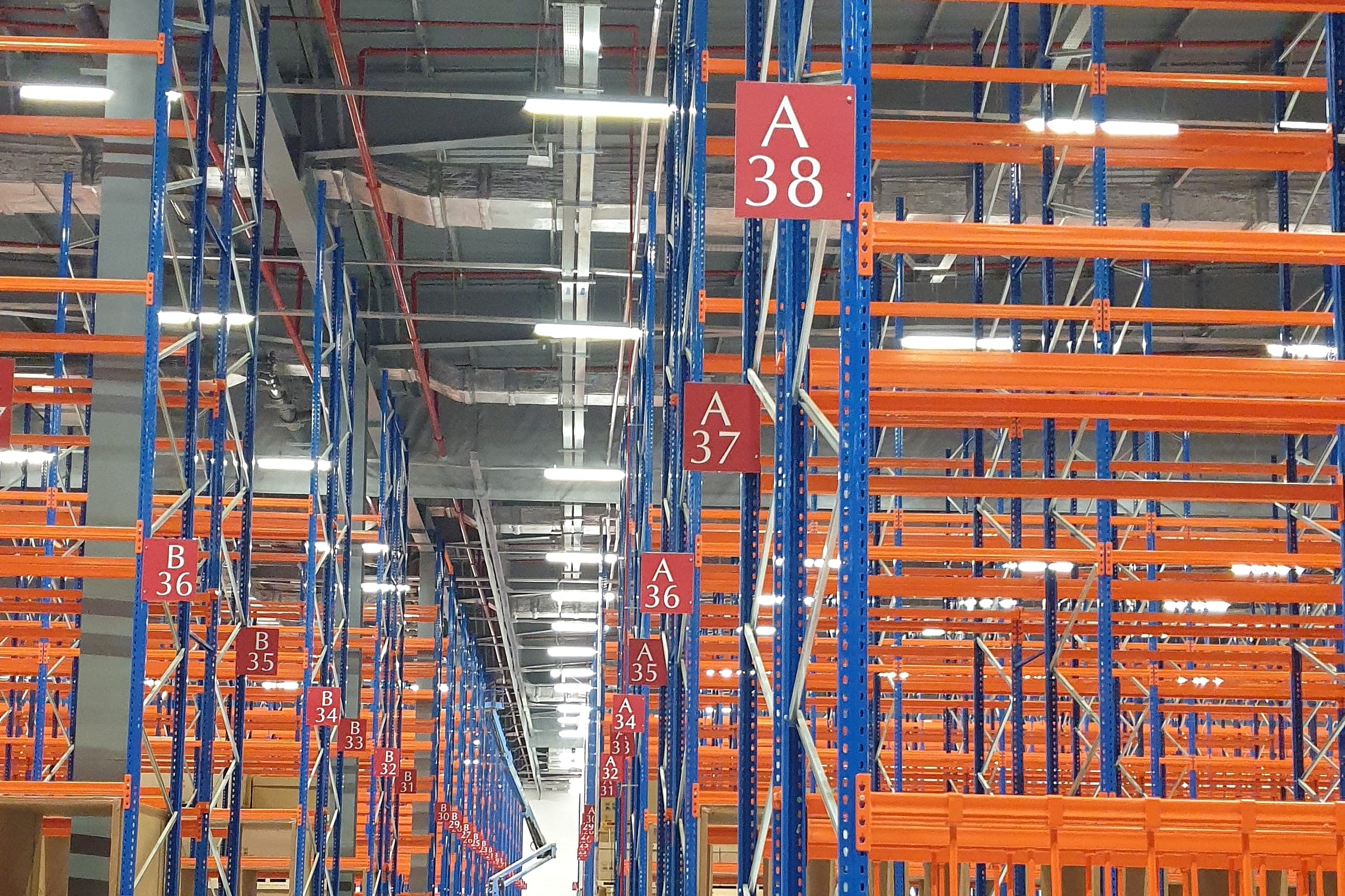 Red aisle marker signs receding down a high-bay warehouse aisle
