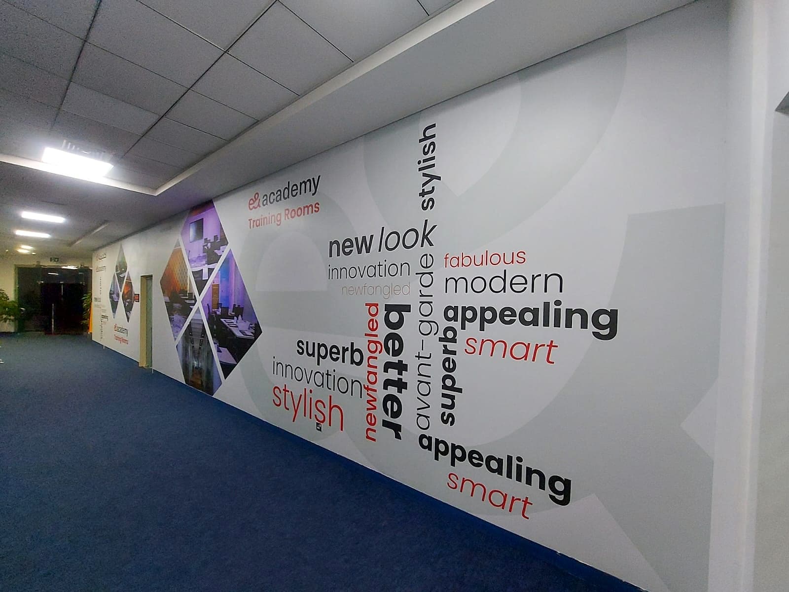 Printed typographic wall graphics along the e& academy training-room corridor
