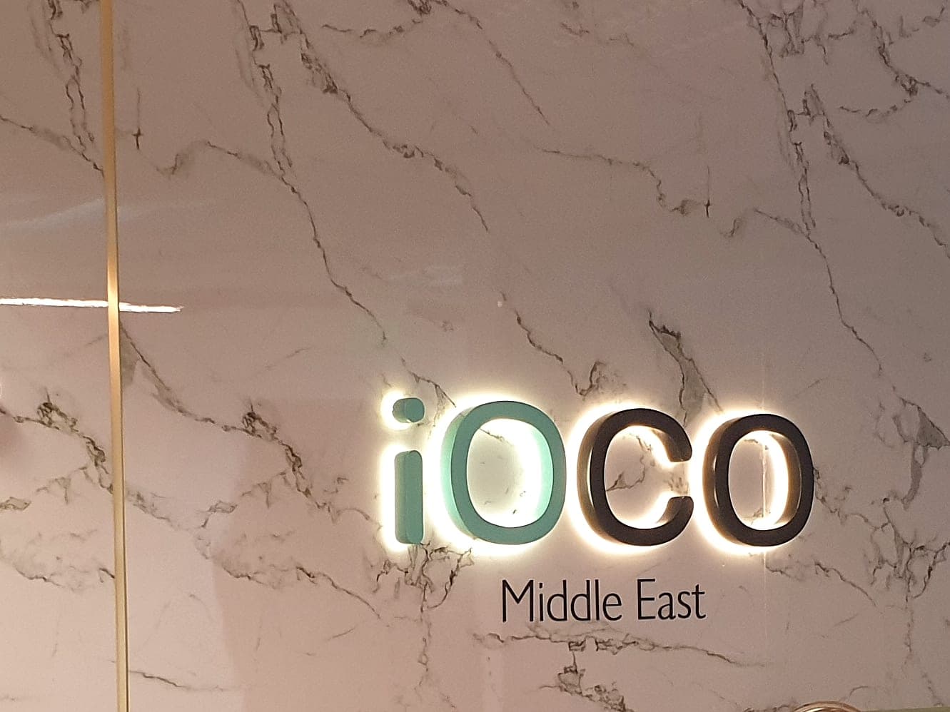 Halo-lit iOCO Middle East logo on a marble reception wall