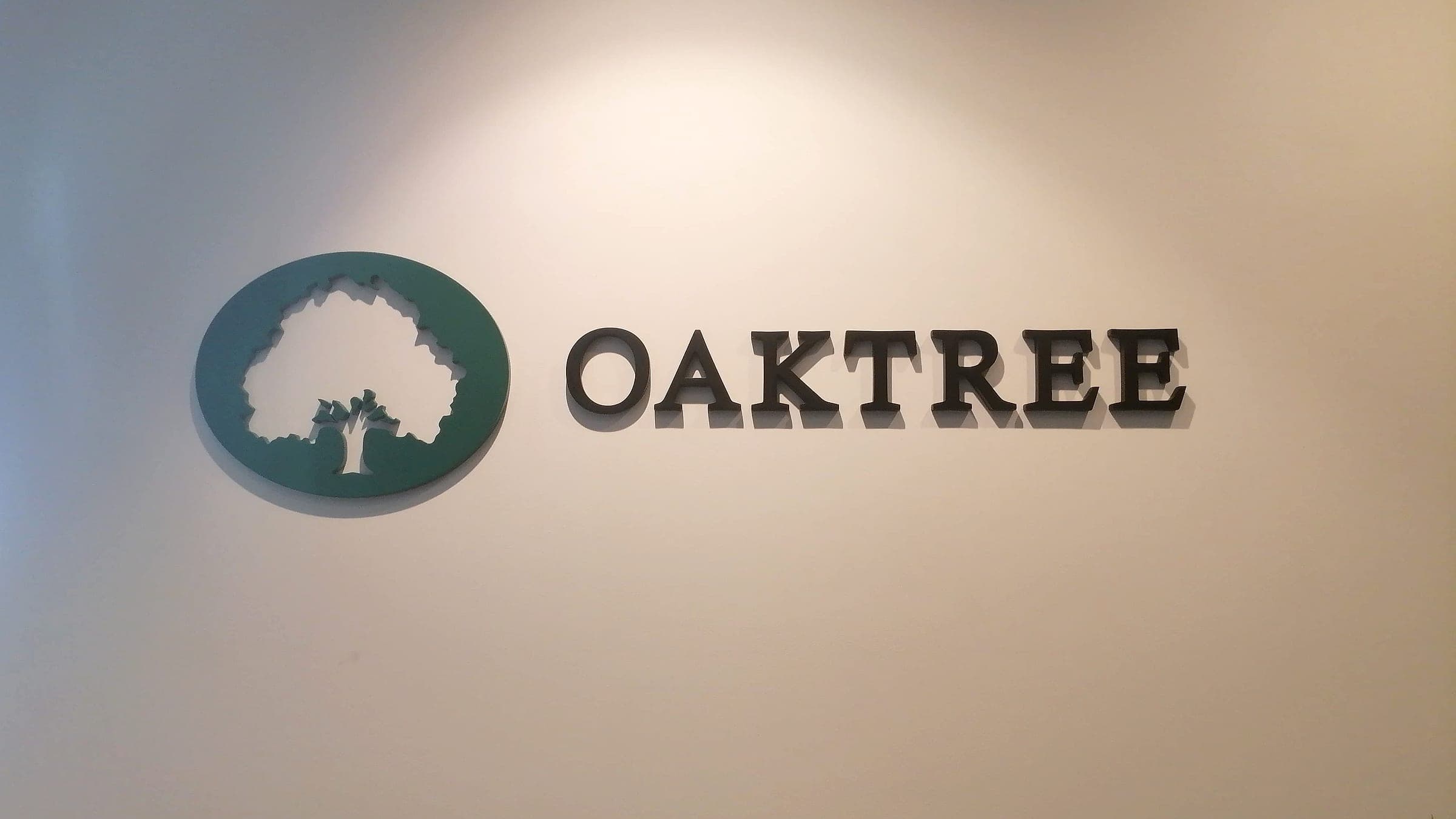 Dimensional Oaktree logo and letters on a softly lit reception wall