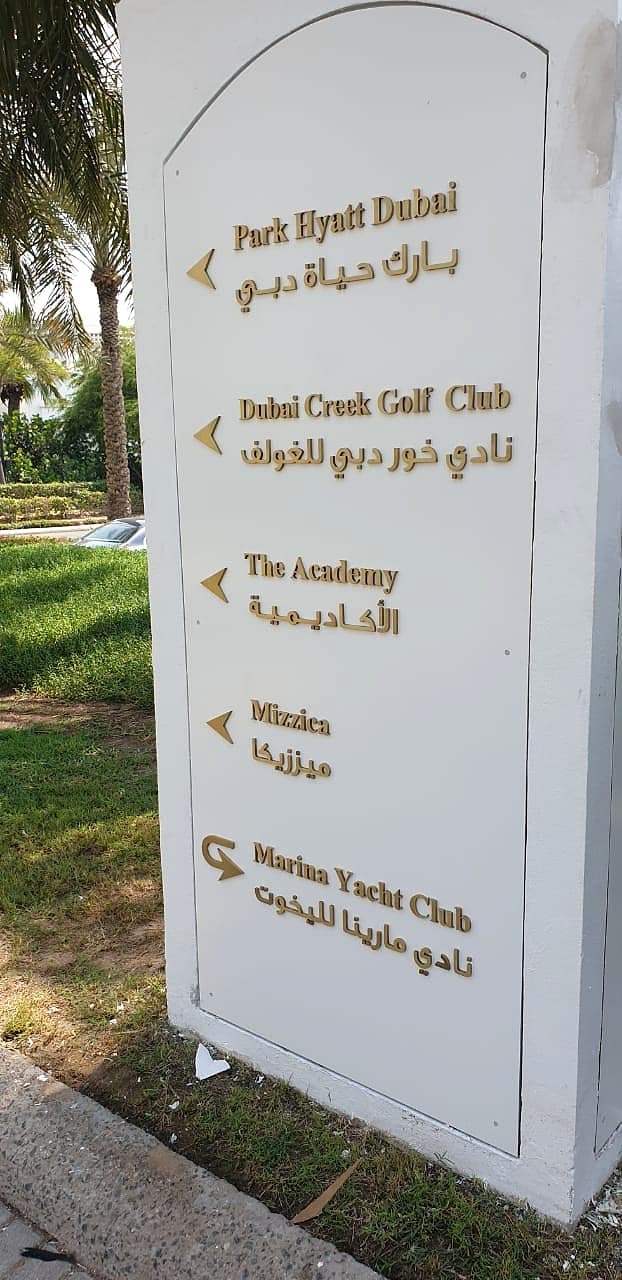 Outdoor bilingual wayfinding totem with gold letters at Park Hyatt Dubai