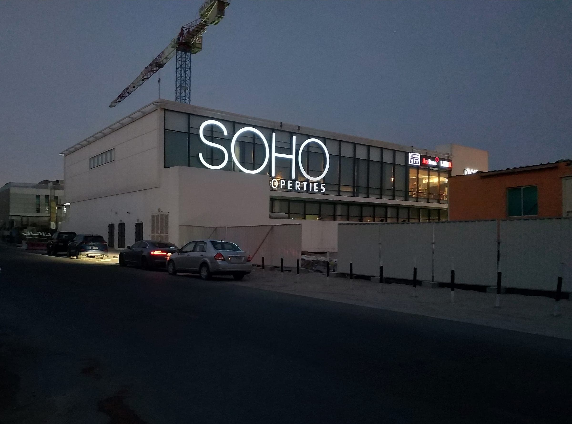 Illuminated SOHO Properties channel letters on a building façade at dusk